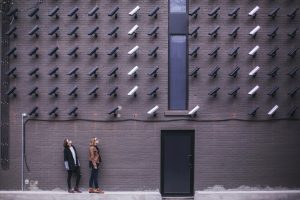 a couple looking up at the wall full of security cameras