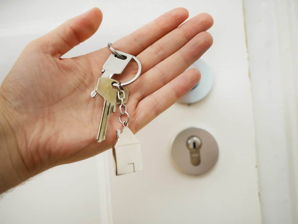 a woman holding keys standing in front of a door