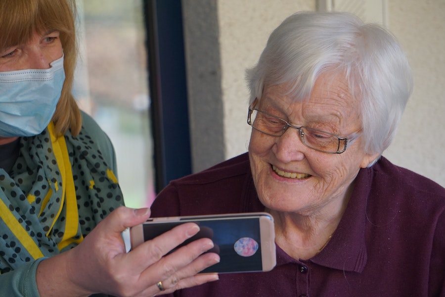 A carer shows an elderly woman her smartphone