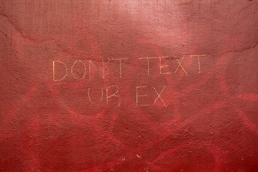 Red wall with ‘Don’t Text Ur Ex’ written on it in yellow