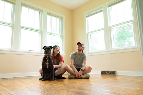 A young family sits on the floor of their empty new home
