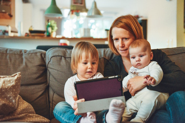 Parent uses an iPad alongside her two young children