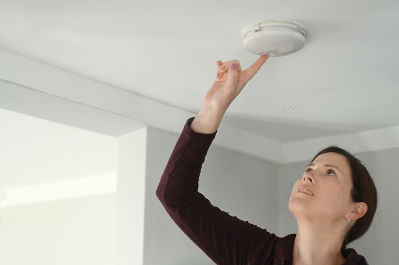 Young adult woman (female age 25-35) checking fire alarm at home.Real people. 