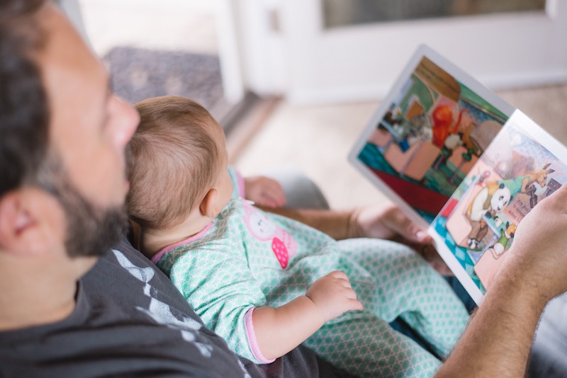 a father is reading a book to his baby