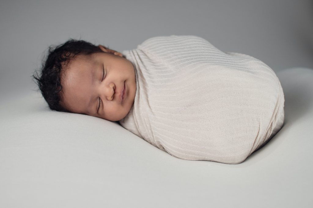 A swaddled newborn sleeps peacefully