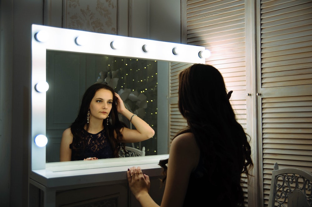 Woman observes herself in a vanity mirror