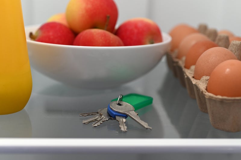 Keys alongside a bowl of apples, juice, and a carton of eggs in a fridge