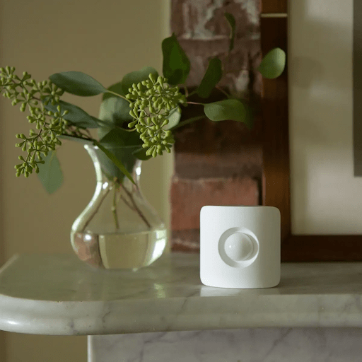 SimpliSafe Motion Sensor on a shelf next to a vase.