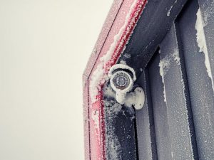 Security video camera in winter. Icicles on the camera block the lens. Frozen security camera in winter with ice crystals.