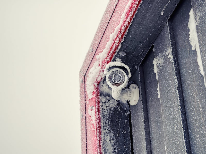 Videocamera di sicurezza in inverno. I ghiaccioli sulla fotocamera bloccano l'obiettivo. Camera di sicurezza congelata in inverno con cristalli di ghiaccio