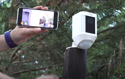 a hand holds a smart phone that shows the livestream of a ring outdoor camera