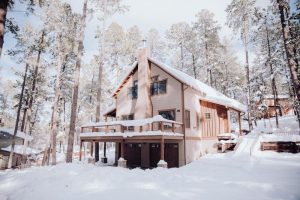 a wooden house in the middle of woods covered in snow