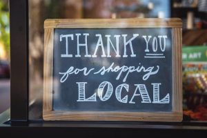 Sign in store window reads, ‘thank you for shopping local’.