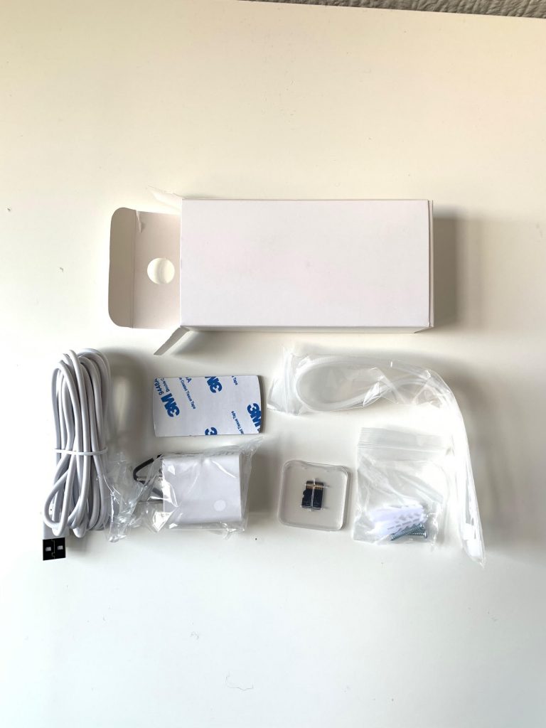 The contents of AlfredCam Plus include the camera, USB C cable, power adapter, mounting sticker, alignment sticker, plastic cable ties, screws and wall plugs, as well as a 64 GB microSD card.