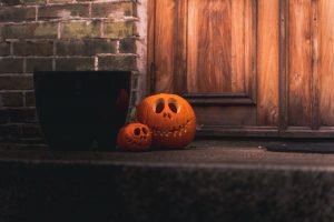 Two carved jack-o-lanterns sit on a doorstep.