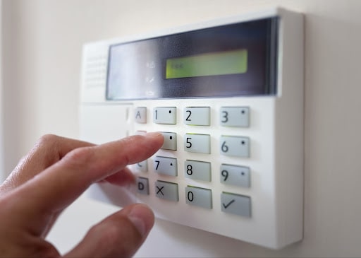 A person setting up an alarm security system via a keypad.