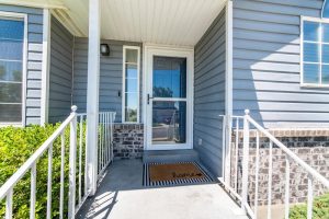 Front porch of a house with glass storm door with sidelight.