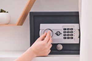 Woman opening modern safe indoors.