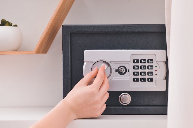 Woman opening modern safe indoors.