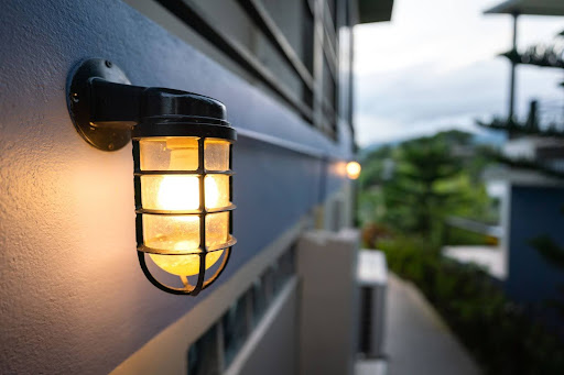 An outdoor wall light switched on in the early evening.