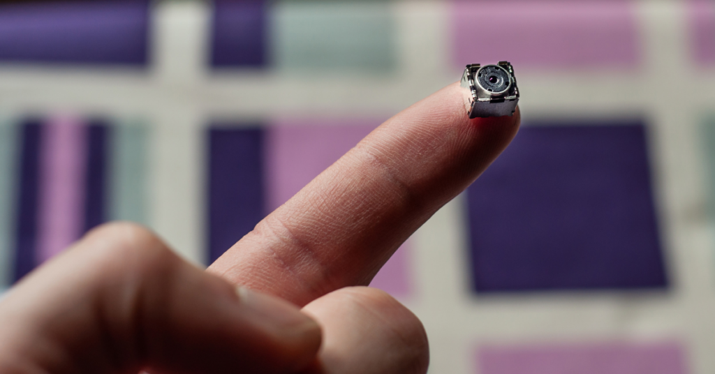 a hand holding a black and small hidden camera
