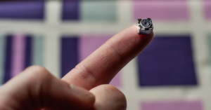 a hand holding a black and small hidden camera
